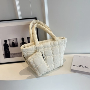Detail of off-white quilted tote bag with matching coin purse on minimalist display