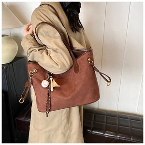Détail du grand sac cabas léopard marron avec breloques de baseball et finitions cuir