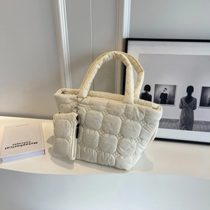Detail of cream quilted tote bag featuring circular cloud texture and matching coin purse charm