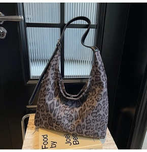 Détail de la bandoulière réglable en cuir noir et boucle argentée sur le sac léopard