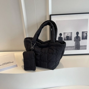 Detail of black quilted bubble tote bag and mini pouch on minimalist white display stand