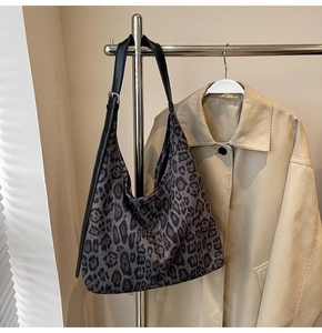 Détail du sac hobo à imprimé léopard avec bandoulière en cuir noir sur un cintre