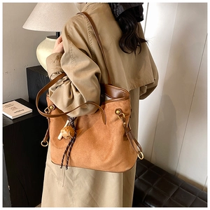Détail d'un cabas en daim marron sur un trench-coat beige avec pendentif ours mignon