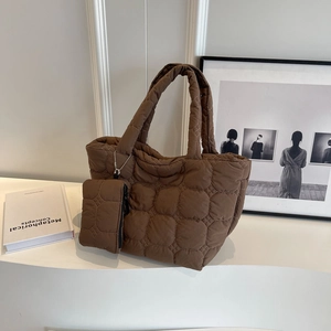 Detail of dark brown quilted tote bag with matching mini pouch on a white pedestal