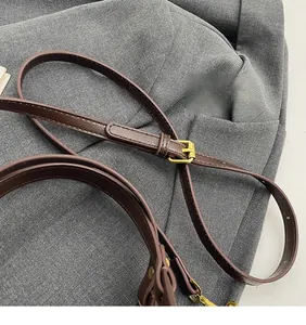 Détail de la bandoulière réglable en cuir marron foncé avec boucle en métal doré