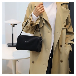 Détail d'un sac polochon noir élégant avec logo blanc porté par un mannequin chic