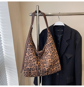 Détail du sac cabas léopard avec bandoulière en cuir suspendu à un cintre en métal