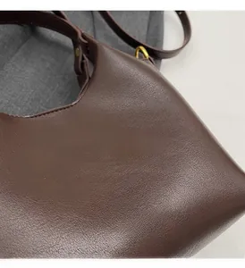 Détail du grand sac cabas en cuir marron foncé avec logo doré et finitions métal