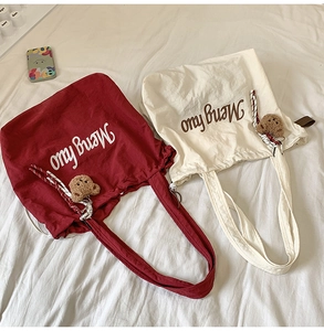 Detail of canvas tote bags with bear charm, ribbon decor, and printed text in a cozy setting