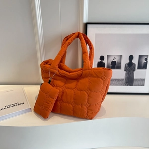 Detailed view of the bright orange quilted tote bag with matching charm pouch