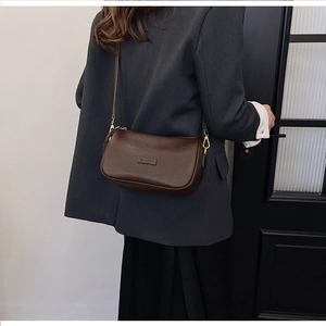 Detailed view of deep brown leather shoulder bag with gold hardware and wide strap