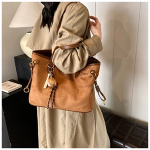 Détail du grand sac cabas en daim léopard avec bordure en cuir marron et breloque poupée