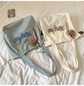 Detail shot of light blue and beige canvas tote bags with plush bear charms