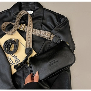Close-up of black PU leather pillow bag featuring textured surface and gold hardware