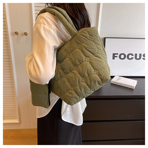 Quilted sage green tote bag with small matching pouch shown on woman's shoulder