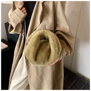 Sac à main en fausse fourrure kaki avec bandoulière chaîne porté sur un long manteau