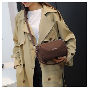Sac Boston marron foncé avec bandoulière porté par un mannequin en trench-coat chic