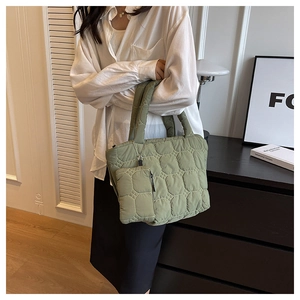 Detail of green quilted tote bag with matching pouch in soft nylon fabric texture