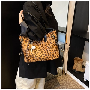 Détail du sac cabas léopard avec anses en cuir noir et accessoire pendentif boule blanche
