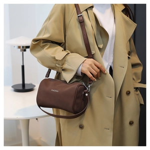 Détail d'un sac polochon marron café avec poignées en cuir et fermetures argentées