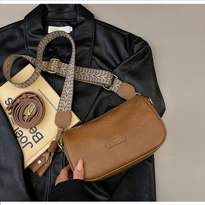 Detail view of brown vintage pillow bag with wide geometric strap on leather jacket