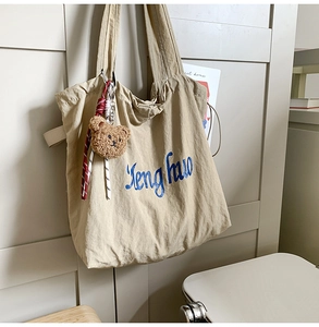Detail of khaki canvas tote with Jenghuo embroidery and plush bear keychain