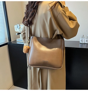 Détail du sac seau marron mat avec breloque ours et logo FASHION & BAGS imprimé