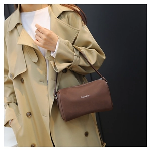 Détail d'un sac bandoulière cylindrique marron foncé avec fermeture éclair argentée