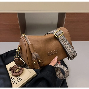 Detailed view of brown boston bag with wide ethnic strap and smooth leather texture