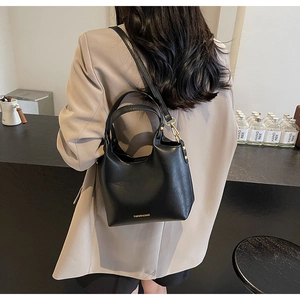 Détail d'un sac seau noir minimaliste avec ferrures dorées et bandoulière amovible