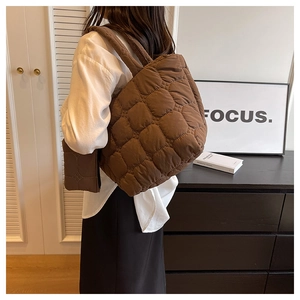 Macro view of brown quilted puffer tote bag with spacious texture and matching small pouch