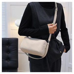 Détail du sac polochon beige avec logo métallique, zip et bandoulière réglable