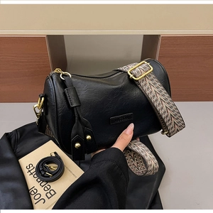 Close-up of black cylinder bag showing fine faux leather texture and retro gold zipper