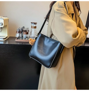 Détail du grand sac cabas noir en similicuir avec texte et pendentif ours marron