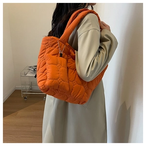 Detail of orange quilted tote bag with matching coin purse shown on a model