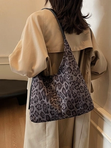 Sac cabas léopard vintage avec longues anses noires porté sur un trench-coat kaki