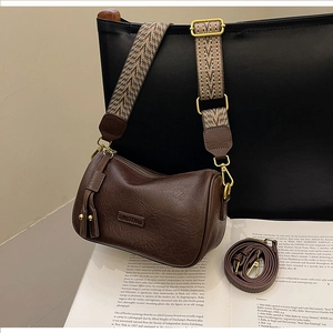 Detail of dark brown leather bag with vintage geometric fabric strap and gold hardware