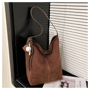 Detail einer braunen Wildleder-Hobo-Tasche mit einem Baseballhandschuh- und Schläger-Anhänger