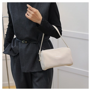 Modèle portant un sac Boston crème en cuir lisse avec fermeture éclair métallique