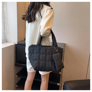 Macro view of black quilted tote bag with matching chain pouch and soft nylon texture