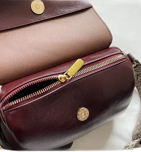 Detailed close-up of smooth zipper and hardware on vintage burgundy cylinder bag
