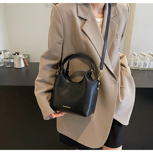 Détail d'un sac seau en cuir noir avec lettrage mode doré et finitions en métal