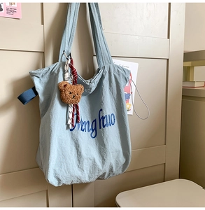 Detail of light blue tote bag with teddy bear charm and Ding huo script print