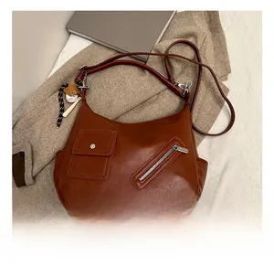 Détail du sac en cuir synthétique marron avec poche à rabat et breloque de baseball