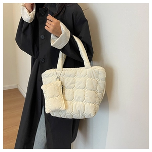 Quilted tote bag detail with detachable mini zipper pouch on shoulder strap