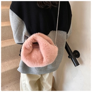 Détail du sac à bandoulière en peluche rose avec chaîne argentée porté par un modèle