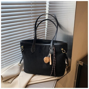 Détail d'un sac cabas en daim noir avec anneau métallique et pendentif de baseball