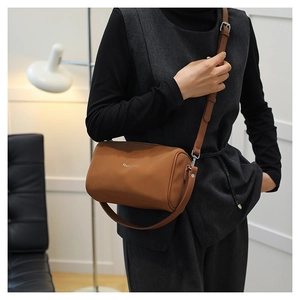 Gros plan du sac bandoulière cylindre en cuir marron avec logo argenté et fine lanière