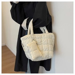 Close-up of beige quilted tote bag with matching detachable pouch on shoulder