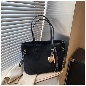 Détail d'un sac cabas en daim noir avec pendentifs de baseball sur une veste légère